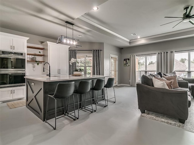 7821 Lindsay Ln, Edmond, OK 73025 - kitchen featuring stainless steel double oven, a kitchen island with sink, a breakfast bar, light countertops, and open floor plan