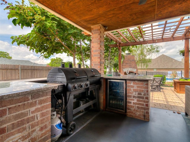 7821 Lindsay Ln, Edmond, OK 73025 - view of patio / terrace featuring wine cooler, an outdoor kitchen, a bar, and a pergola
