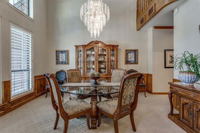 10116 Thompson Ave, Yukon, OK 73099 - dining area featuring a high ceiling, light carpet, a chandelier, and wainscoting