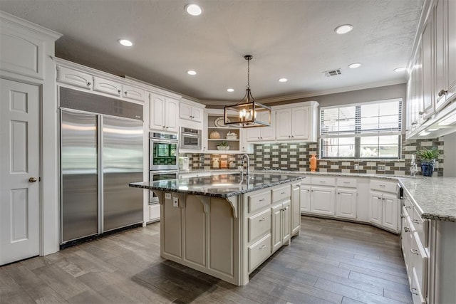 10116 Thompson Ave, Yukon, OK 73099 - kitchen featuring stainless steel appliances, backsplash, dark stone countertops, white cabinetry, and ornamental molding