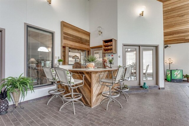 10116 Thompson Ave, Yukon, OK 73099 - kitchen featuring high vaulted ceiling, brick flooring, and a kitchen bar