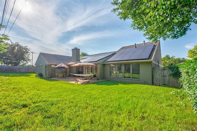6348 Hyde Park Dr, Oklahoma City, OK 73162 - back of property featuring roof mounted solar panels, a patio area, a fenced backyard, a chimney, and brick siding