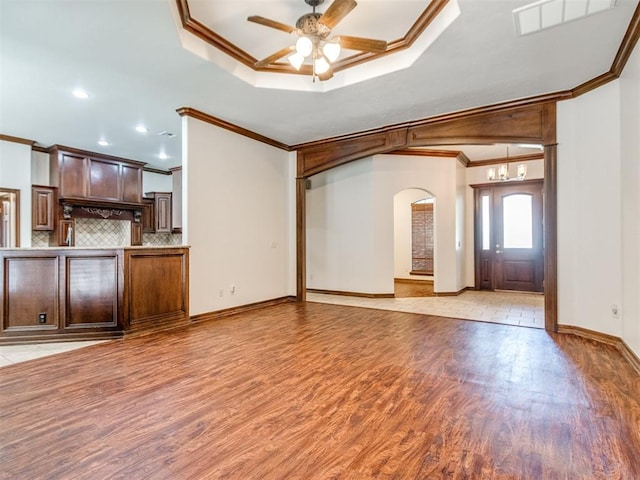 17104 Wales Green Ave, Edmond, OK 73012 - unfurnished living room featuring ornamental molding, arched walkways, light wood-style floors, a ceiling fan, and a chandelier