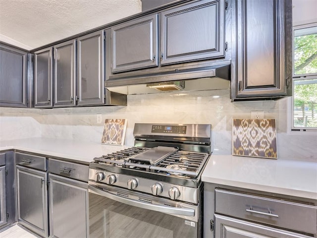 9200 Hollow Rd, Newalla, OK 74857 - kitchen featuring stainless steel gas range, under cabinet range hood, light countertops, decorative backsplash, and a textured ceiling
