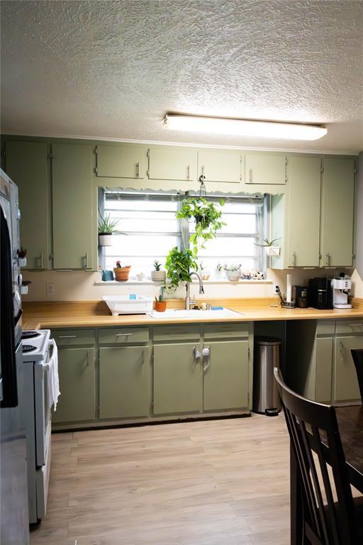 1702 W Boyd St, Norman, OK 73069 - kitchen featuring green cabinets, white range oven, a textured ceiling, and light wood finished floors