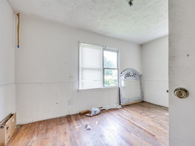 9424 NE 28th St, Oklahoma City, OK 73141 - empty room with hardwood / wood-style flooring, a textured ceiling, and wainscoting