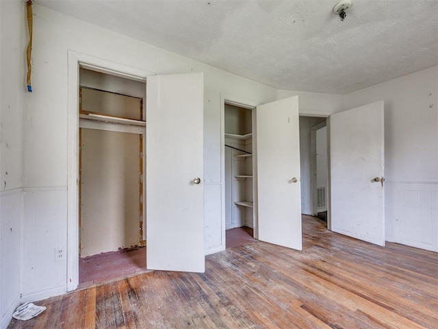 9424 NE 28th St, Oklahoma City, OK 73141 - unfurnished bedroom with hardwood / wood-style floors, a textured ceiling, and two closets