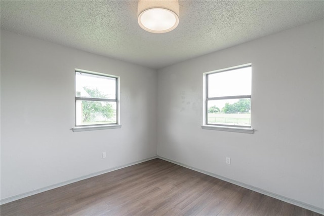 4720 S Youngs Blvd, Oklahoma City, OK 73119 - empty room featuring wood finished floors, plenty of natural light, and a textured ceiling