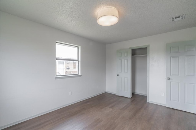 4720 S Youngs Blvd, Oklahoma City, OK 73119 - unfurnished bedroom featuring a textured ceiling, wood finished floors, and a closet