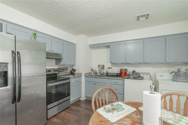 4720 S Youngs Blvd, Oklahoma City, OK 73119 - kitchen with appliances with stainless steel finishes, washing machine and dryer, under cabinet range hood, dark wood-style flooring, and a textured ceiling