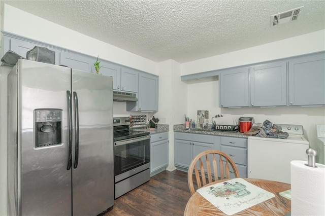 4720 S Youngs Blvd, Oklahoma City, OK 73119 - kitchen featuring stainless steel appliances, under cabinet range hood, dark wood-style flooring, washer / clothes dryer, and a textured ceiling