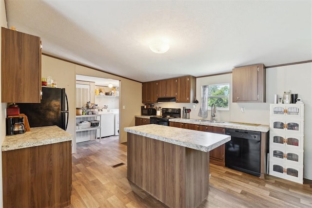 4040 Logan Hills Dr, Guthrie, OK 73044 - kitchen with black appliances, light wood-style flooring, light countertops, under cabinet range hood, and vaulted ceiling