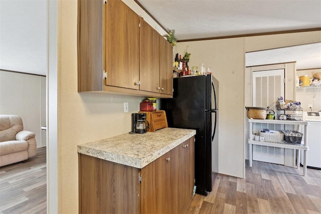 4040 Logan Hills Dr, Guthrie, OK 73044 - kitchen with washer / dryer, light wood-style floors, light countertops, freestanding refrigerator, and brown cabinets