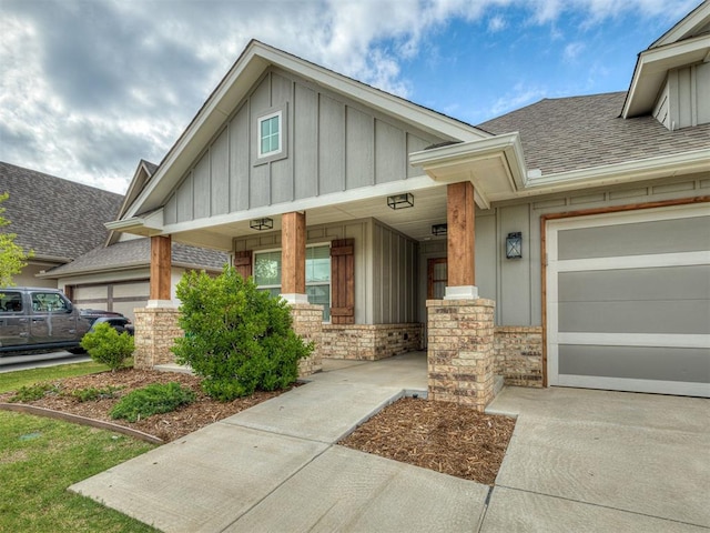 2436 NW 179th St, Edmond, OK 73012 - view of front of home featuring board and batten siding, roof with shingles, a porch, an attached garage, and stone siding