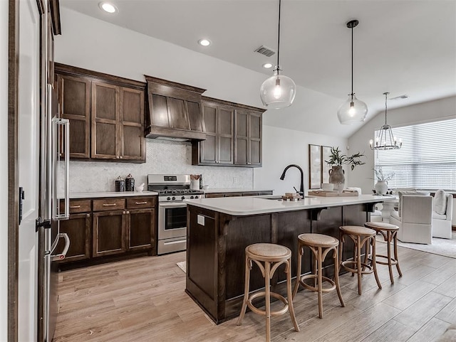2436 NW 179th St, Edmond, OK 73012 - kitchen featuring stainless steel range with gas cooktop, custom exhaust hood, washer and clothes dryer, dark brown cabinetry, and light countertops