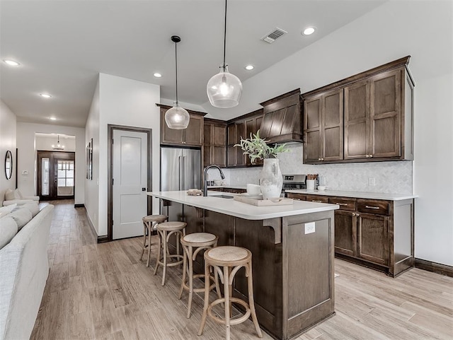 2436 NW 179th St, Edmond, OK 73012 - kitchen with dark brown cabinetry, custom exhaust hood, high quality fridge, light countertops, and light wood-style floors