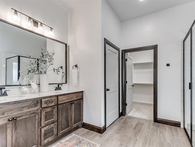 2436 NW 179th St, Edmond, OK 73012 - bathroom with wood finished floors, double vanity, a stall shower, and a spacious closet
