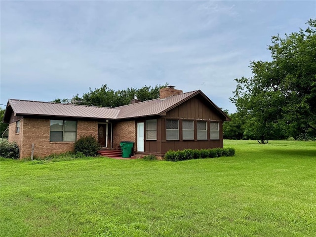 311 Parker St, Waurika, OK 73573 - view of front of home featuring a front lawn, a metal roof, a chimney, and brick siding