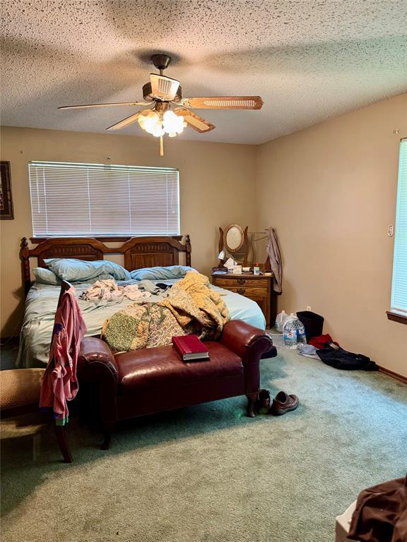 311 Parker St, Waurika, OK 73573 - carpeted bedroom featuring ceiling fan and a textured ceiling