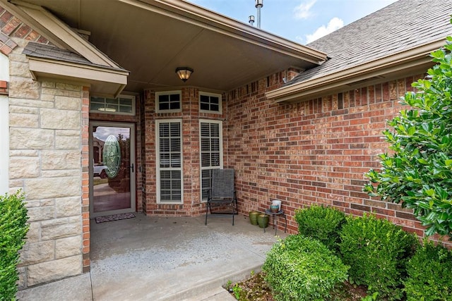 716 SW 157th St, Oklahoma City, OK 73170 - property entrance featuring a shingled roof, brick siding, and a patio area