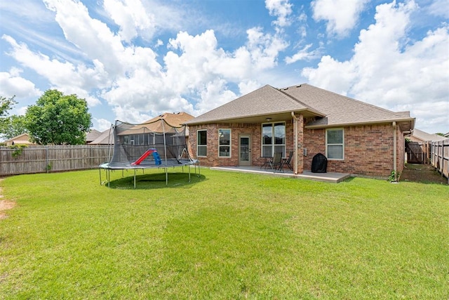 716 SW 157th St, Oklahoma City, OK 73170 - rear view of property with a trampoline, a patio area, a fenced backyard, roof with shingles, and brick siding