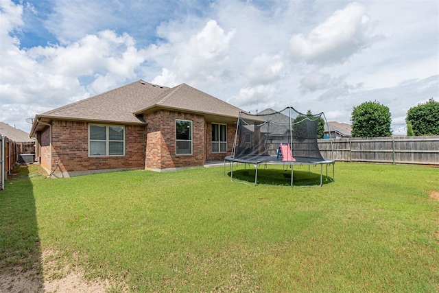 716 SW 157th St, Oklahoma City, OK 73170 - back of property featuring a trampoline, brick siding, roof with shingles, and a fenced backyard