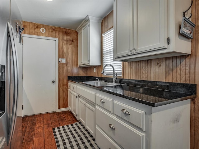 1209 Dakota St, Norman, OK 73069 - kitchen featuring stainless steel fridge with ice dispenser, dark wood-style floors, wood walls, and white cabinets