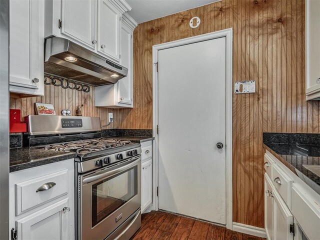 1209 Dakota St, Norman, OK 73069 - kitchen with stainless steel range with gas cooktop, under cabinet range hood, white cabinetry, wooden walls, and dark wood-type flooring