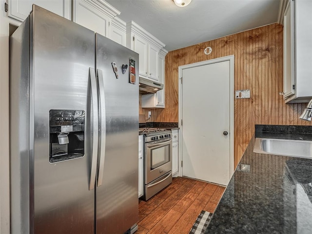 1209 Dakota St, Norman, OK 73069 - kitchen featuring appliances with stainless steel finishes, under cabinet range hood, white cabinets, dark wood-style floors, and dark stone counters