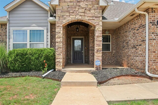 8401 NW 140th St, Oklahoma City, OK 73142 - entrance to property featuring brick siding, a shingled roof, a porch, and stone siding