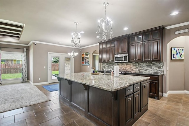 8401 NW 140th St, Oklahoma City, OK 73142 - kitchen featuring stainless steel microwave, arched walkways, a chandelier, a kitchen bar, and backsplash