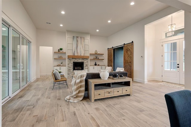 1801 Cedar Valley Mnr, Guthrie, OK 73044 - living room featuring a barn door, light wood-style flooring, recessed lighting, a fireplace, and a chandelier
