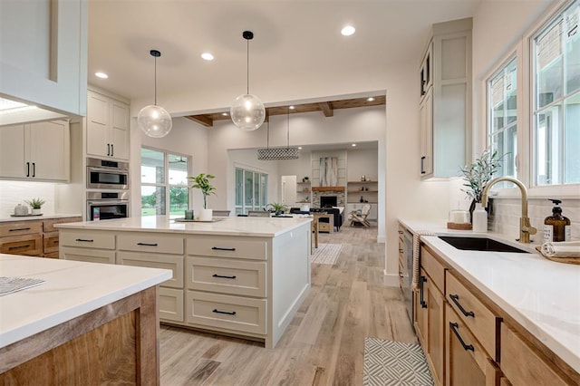 1801 Cedar Valley Mnr, Guthrie, OK 73044 - kitchen featuring decorative backsplash, light wood-style flooring, recessed lighting, a stone fireplace, and hanging light fixtures