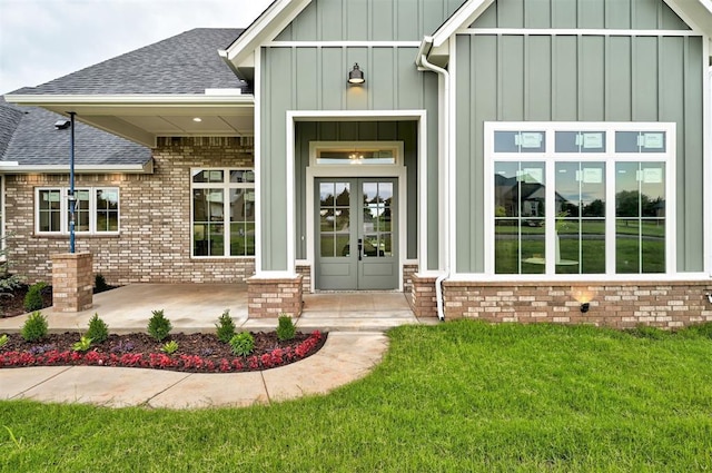 1801 Cedar Valley Mnr, Guthrie, OK 73044 - property entrance featuring board and batten siding, roof with shingles, french doors, brick siding, and a yard
