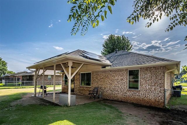 912 S Boynton Ave, El Reno, OK 73036 - rear view of house featuring a ceiling fan, a patio area, a fenced backyard, roof mounted solar panels, and brick siding