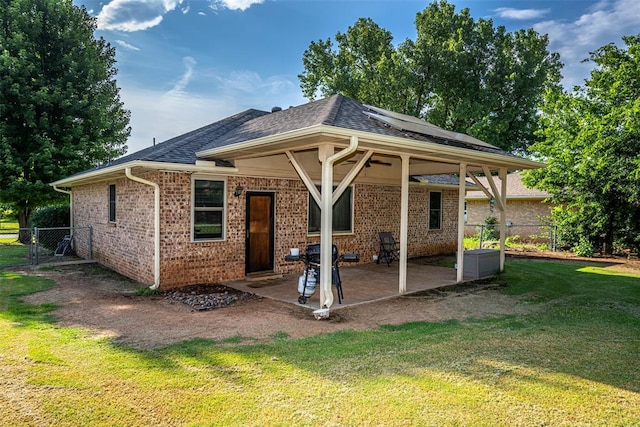 912 S Boynton Ave, El Reno, OK 73036 - back of property featuring a patio, brick siding, solar panels, and a shingled roof
