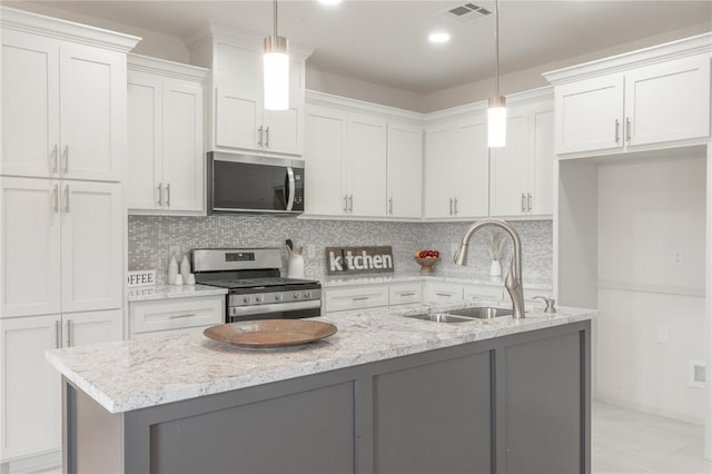 316 SE 45th St, Oklahoma City, OK 73129 - kitchen featuring appliances with stainless steel finishes, white cabinets, decorative backsplash, a kitchen island with sink, and light stone counters