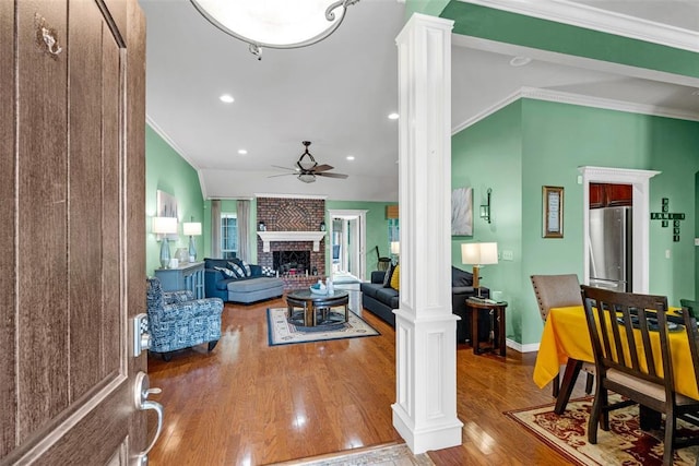817 NW 76th St, Lawton, OK 73505 - living area featuring ornate columns, a ceiling fan, crown molding, wood finished floors, and a brick fireplace