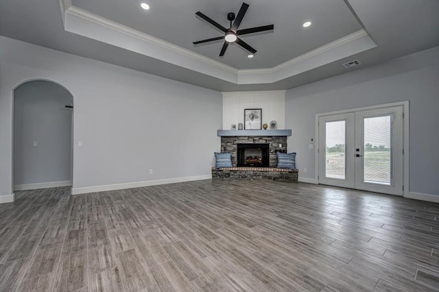 1890 E Industrial Rd, Guthrie, OK 73044 - unfurnished living room featuring a raised ceiling, ceiling fan, crown molding, arched walkways, and wood finished floors