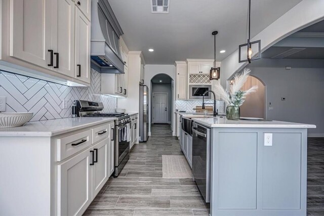 1890 E Industrial Rd, Guthrie, OK 73044 - kitchen featuring stainless steel appliances, custom exhaust hood, arched walkways, light countertops, and recessed lighting