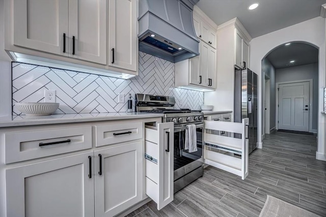 1890 E Industrial Rd, Guthrie, OK 73044 - kitchen with stainless steel appliances, custom range hood, arched walkways, tasteful backsplash, and light countertops