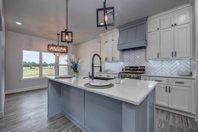 1890 E Industrial Rd, Guthrie, OK 73044 - kitchen with stainless steel range with gas stovetop, custom range hood, backsplash, a kitchen island with sink, and dark wood-type flooring