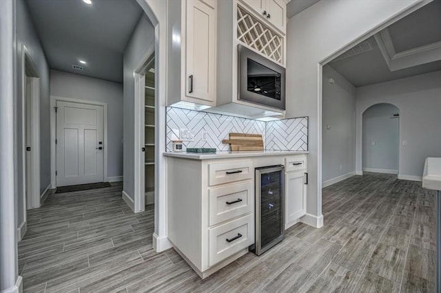 1890 E Industrial Rd, Guthrie, OK 73044 - kitchen with beverage cooler, arched walkways, light countertops, light wood finished floors, and backsplash