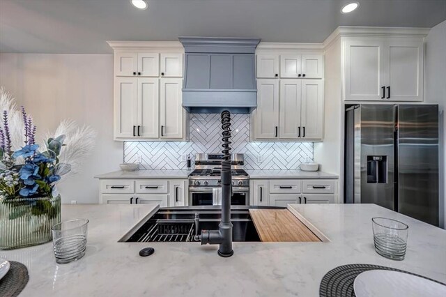 1890 E Industrial Rd, Guthrie, OK 73044 - kitchen with stainless steel appliances, premium range hood, light stone counters, tasteful backsplash, and recessed lighting