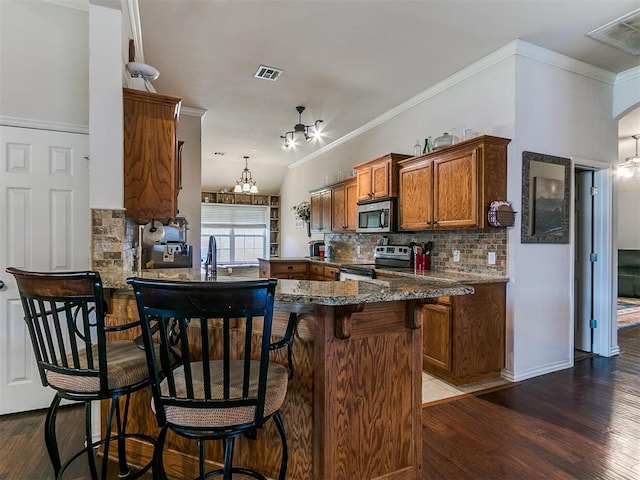 1205 NW 190th Pl, Edmond, OK 73012 - kitchen with appliances with stainless steel finishes, decorative backsplash, dark wood-style floors, brown cabinets, and crown molding