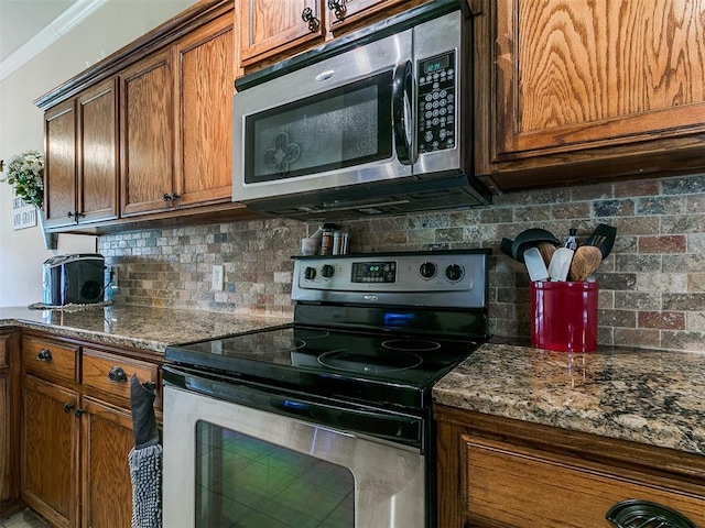 1205 NW 190th Pl, Edmond, OK 73012 - kitchen with appliances with stainless steel finishes, tasteful backsplash, dark stone countertops, crown molding, and brown cabinets