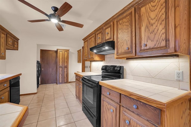 3217 Quail Cir, Altus, OK 73521 - kitchen featuring black appliances, under cabinet range hood, tile counters, backsplash, and a ceiling fan