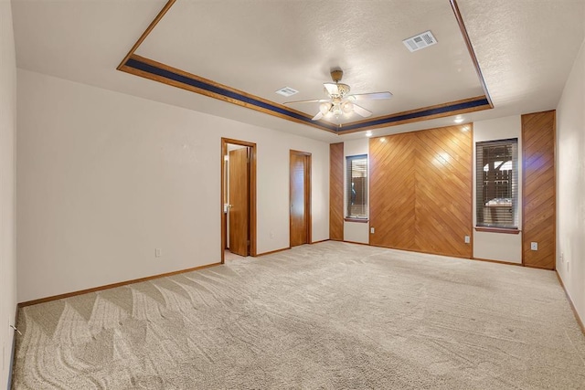 3217 Quail Cir, Altus, OK 73521 - spare room with a tray ceiling, a ceiling fan, carpet, wood walls, and a textured ceiling