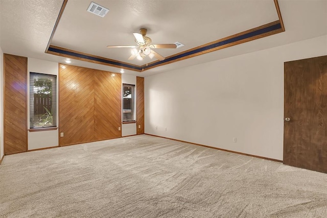 3217 Quail Cir, Altus, OK 73521 - unfurnished room featuring a raised ceiling, a ceiling fan, carpet, and wooden walls