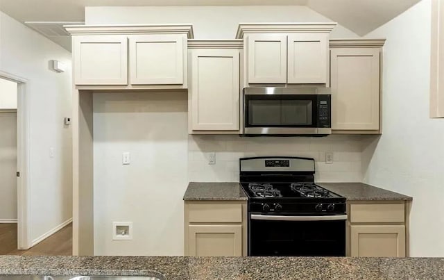1426 SW Oklahoma Ave, Lawton, OK 73501 - kitchen with stainless steel microwave, black range with gas cooktop, decorative backsplash, and dark stone countertops